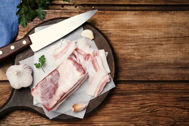 Photo of Tasty salt pork with garlic and parsley on wooden table, flat lay. Space for text