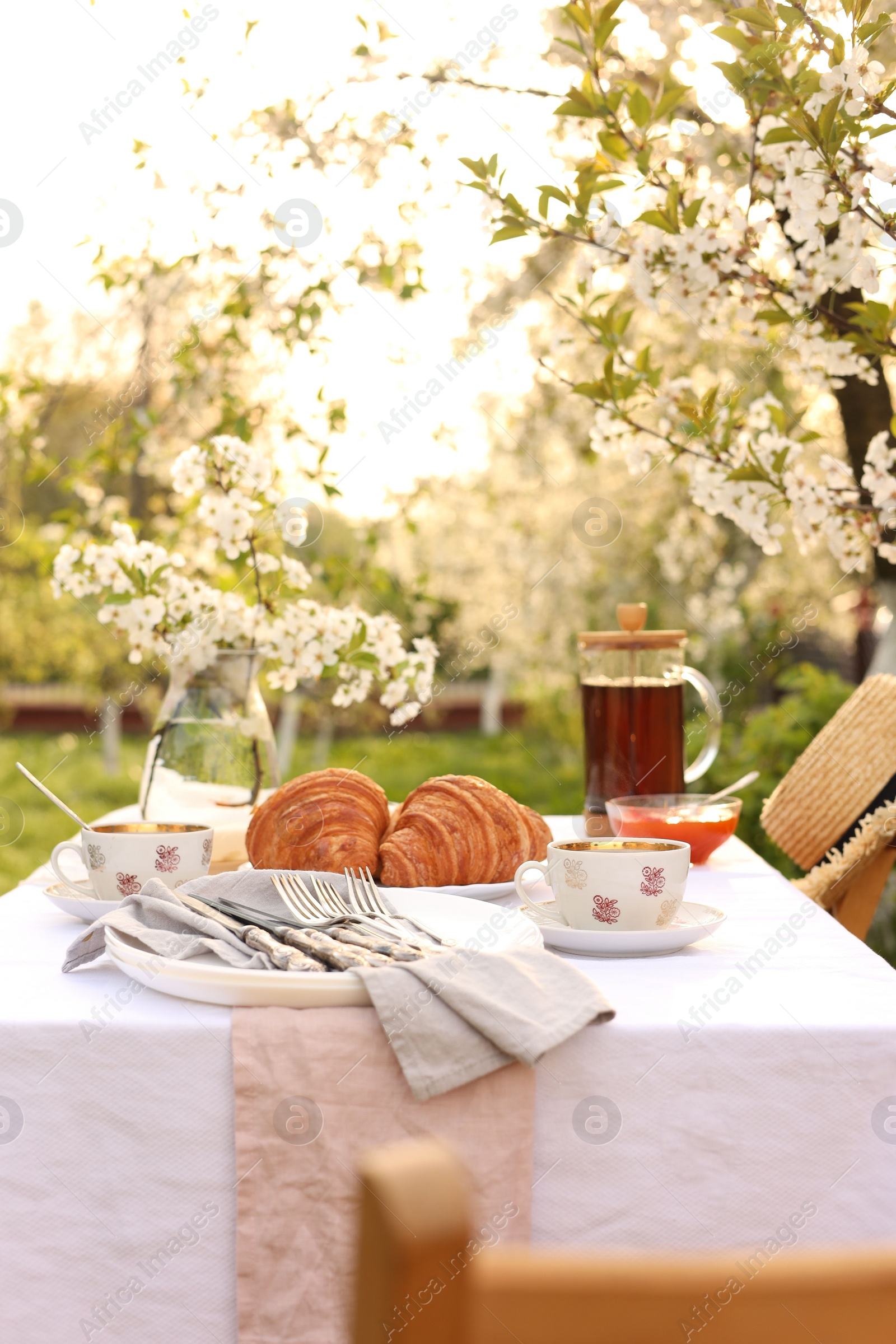 Photo of Stylish table setting with tea and croissants in spring garden