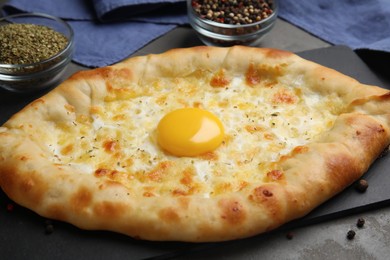 Fresh homemade khachapuri with cheese and egg on grey table, closeup