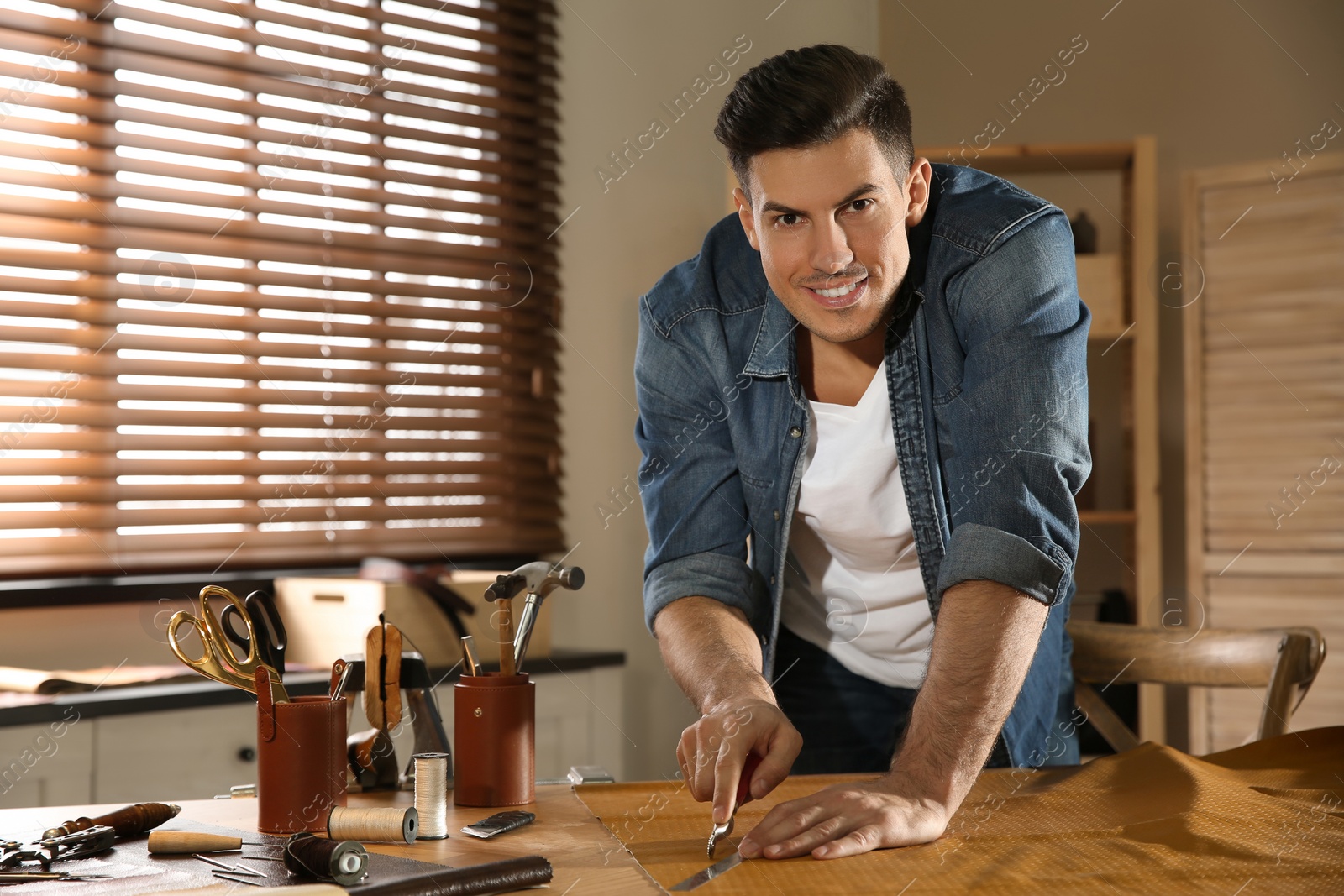 Photo of Man marking leather with roller in workshop