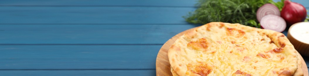 Image of Delicious Megrelian khachapuri on blue wooden table, banner design. Space for text