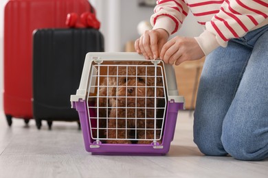 Photo of Woman closing carrier with her pet before travelling indoors, closeup