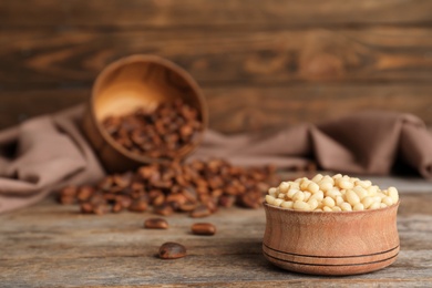 Bowl with pine nuts on wooden table. Space for text