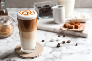 Glass with delicious caramel latte on table