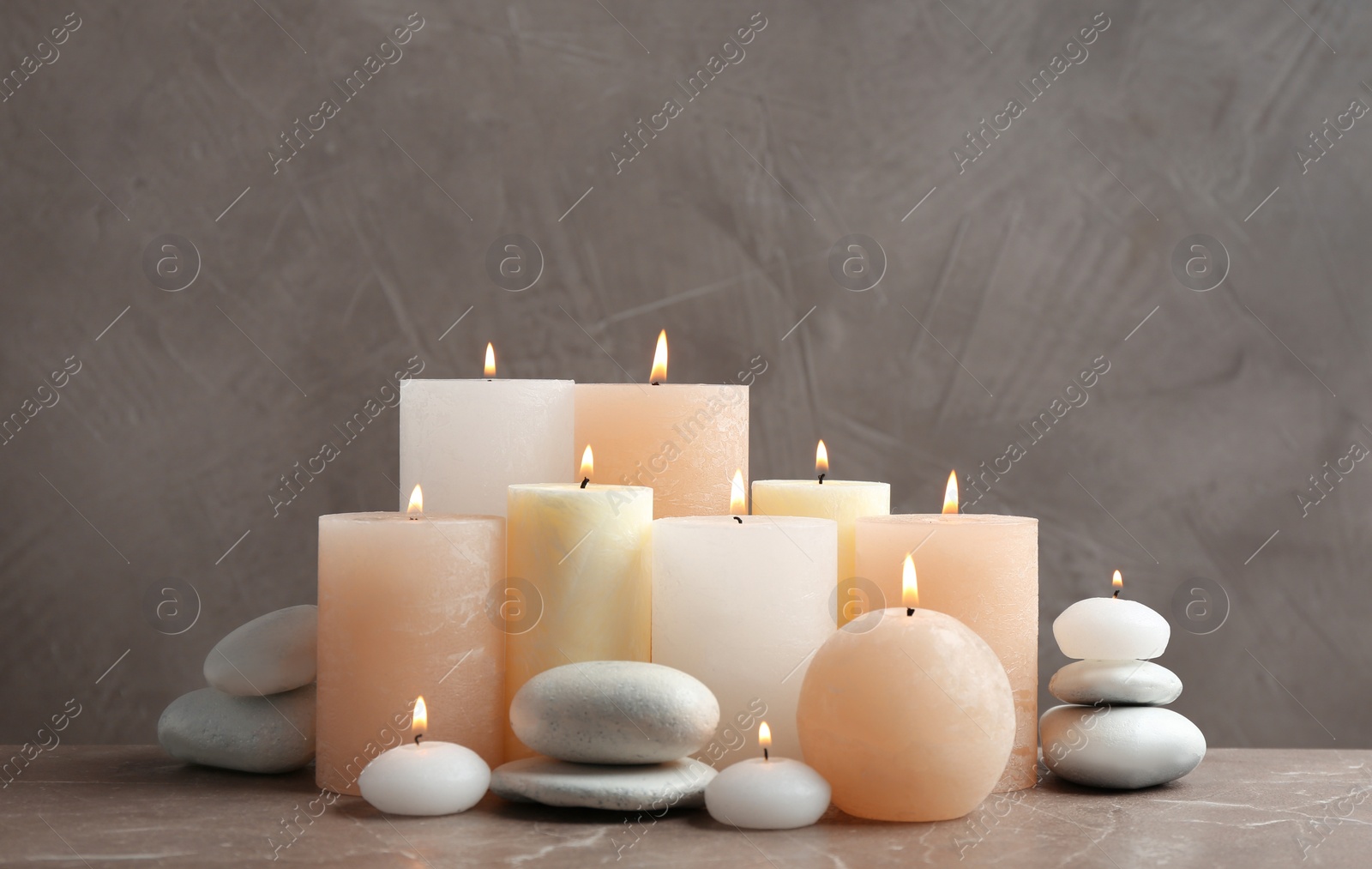 Photo of Beautiful composition with candles and stones on table against grey background