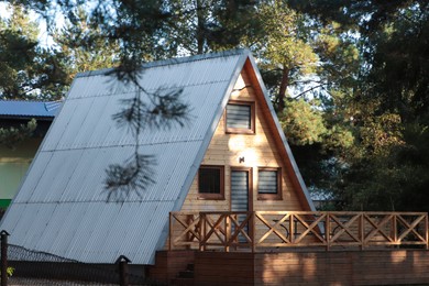 Picturesque view of modern wooden house with veranda near forest on sunny day