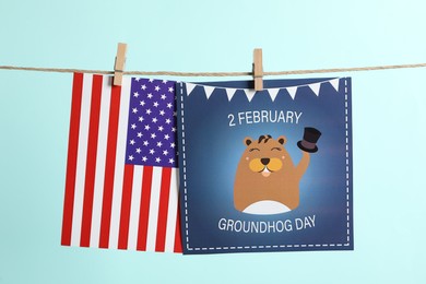 Photo of Happy Groundhog Day greeting card and American flag hanging on turquoise background