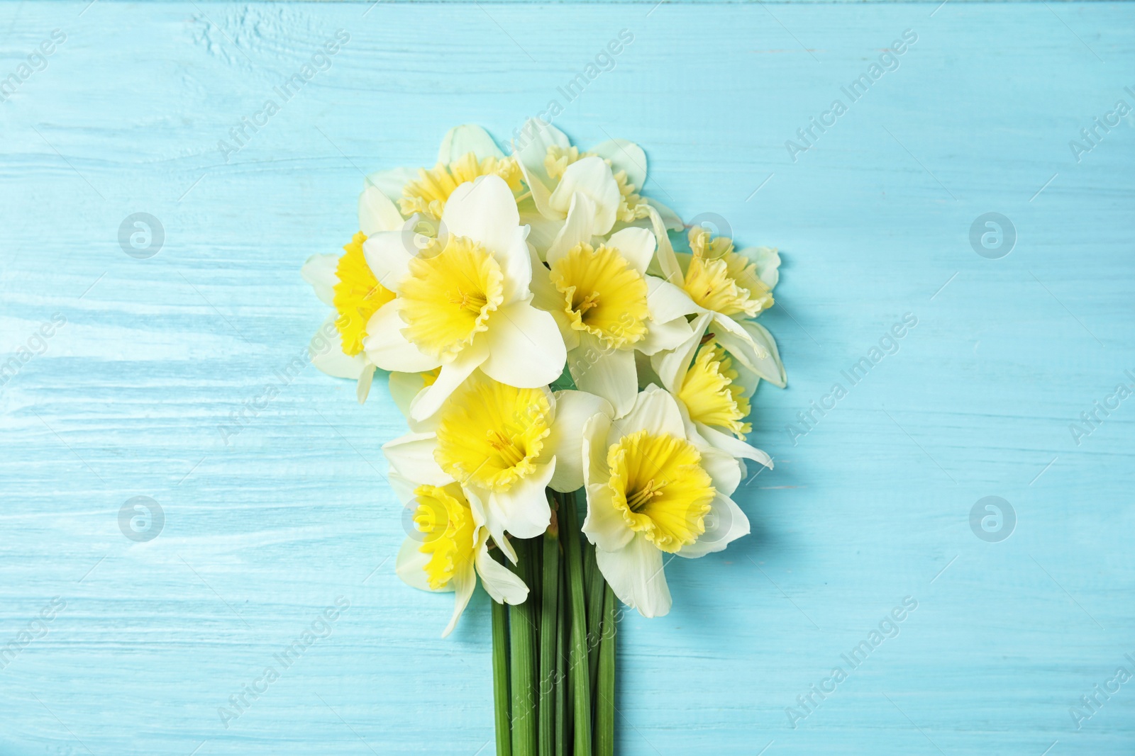 Photo of Bouquet of daffodils on wooden background, top view. Fresh spring flowers