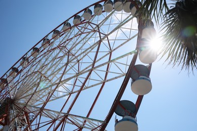 Photo of Beautiful Ferris wheel against blue sky on sunny day, low angle view