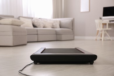 Photo of Modern walking treadmill in living room. Home gym equipment