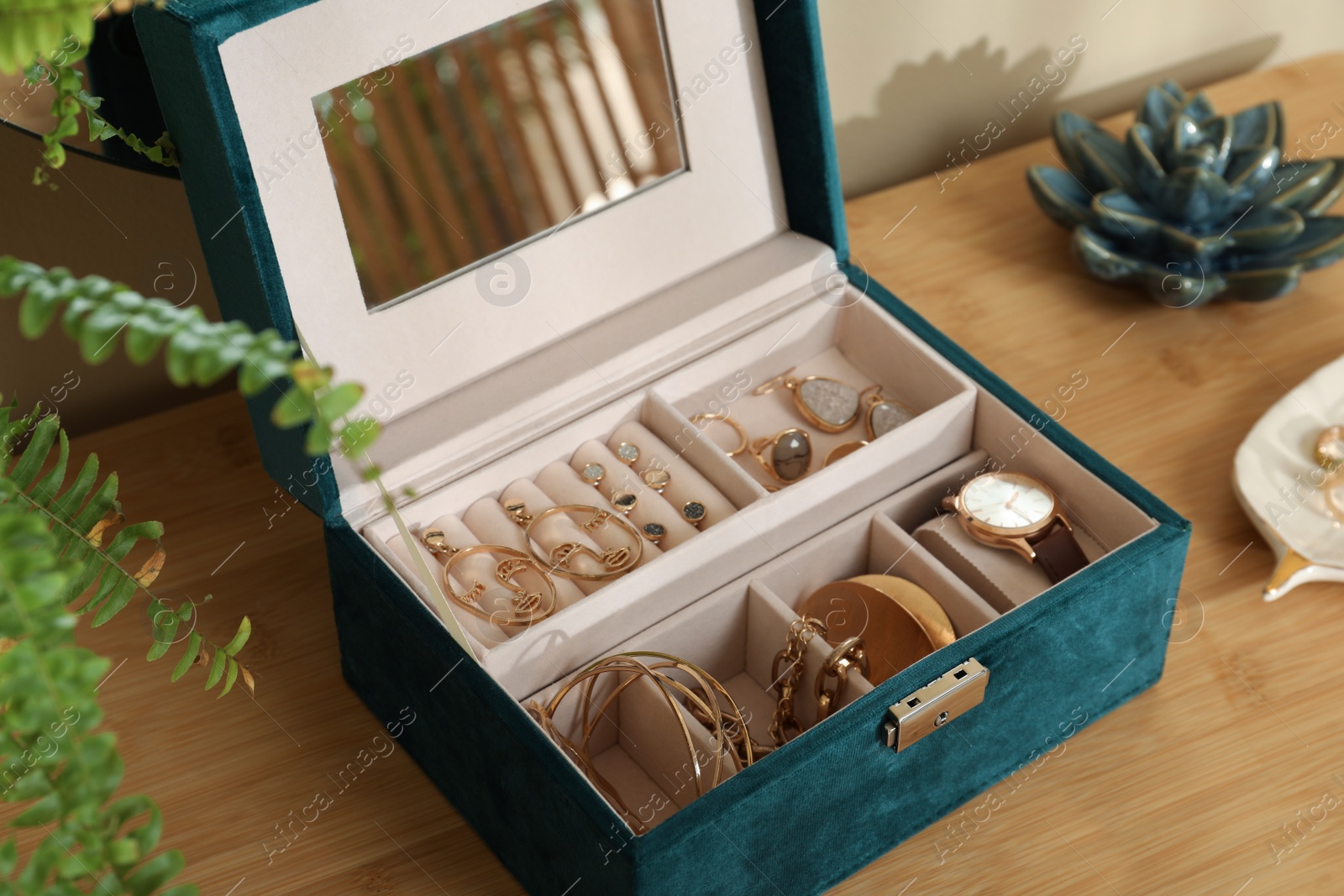 Photo of Elegant jewelry box with beautiful bijouterie and wristwatch on wooden table