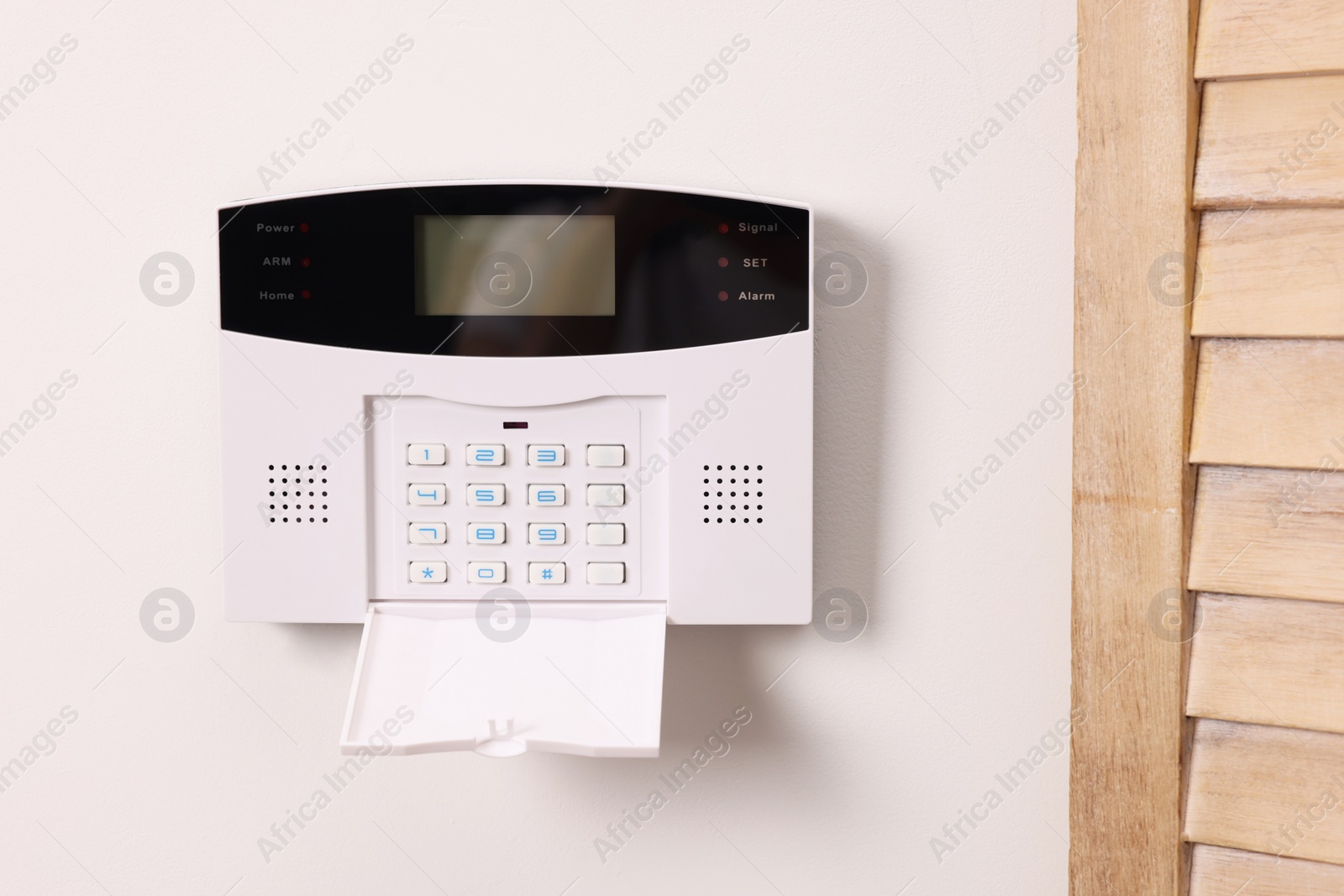 Photo of Home security alarm system on white wall indoors