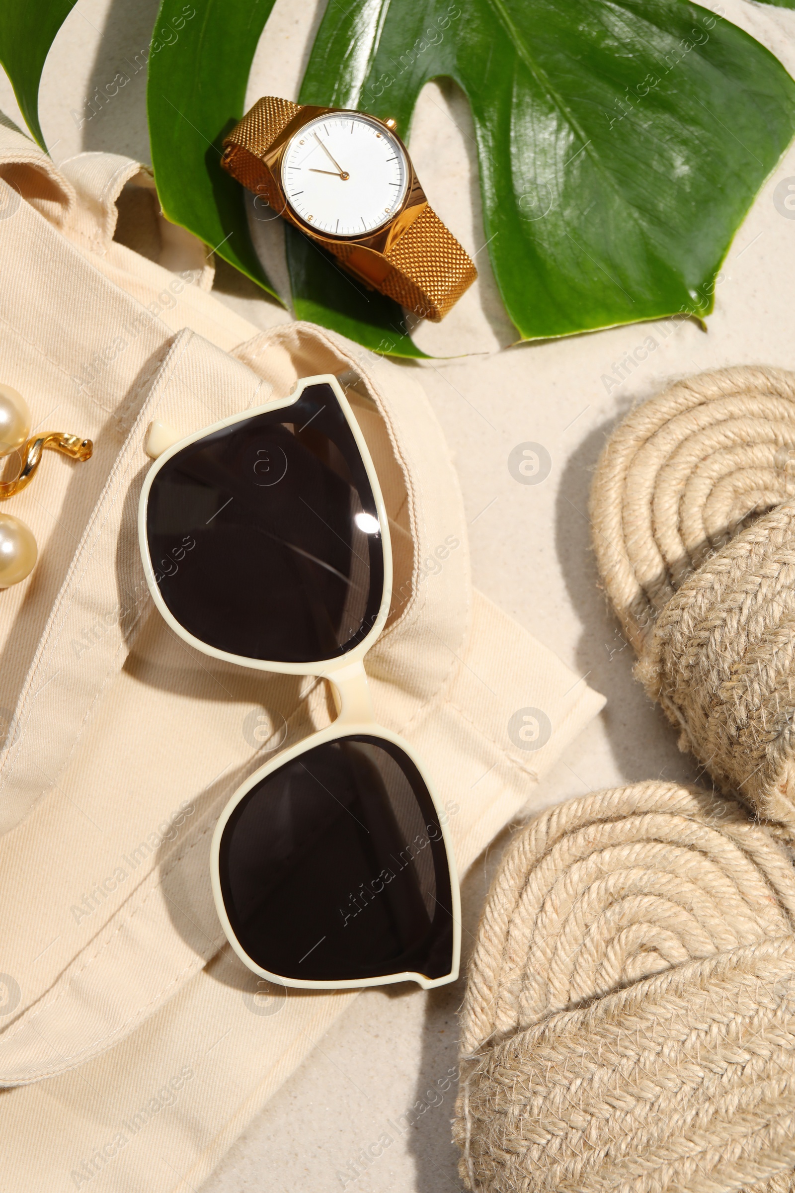 Photo of Flat lay composition with stylish sunglasses and other fashionable accessories on sand