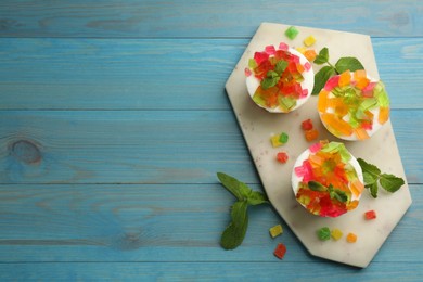 Photo of Delicious broken glass jelly dessert on light blue wooden table, flat lay. Space for text