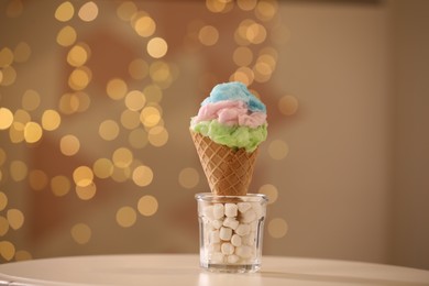 Photo of Sweet cotton candy in waffle cone on table against blurred lights