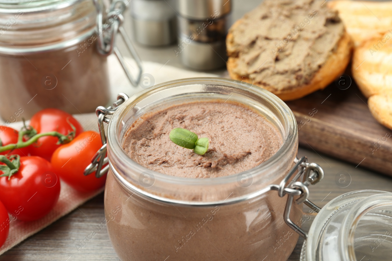 Photo of Glass jar with delicious liver pate on wooden table, closeup