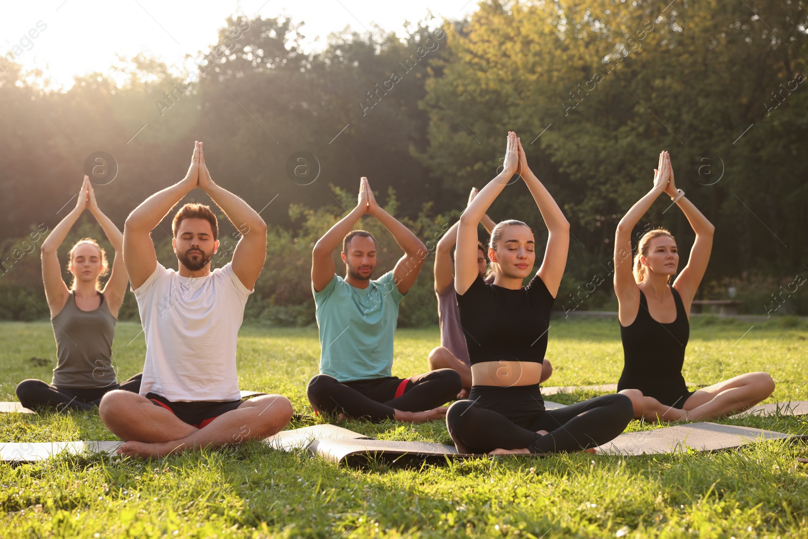 Photo of Group of people practicing yoga on mats outdoors