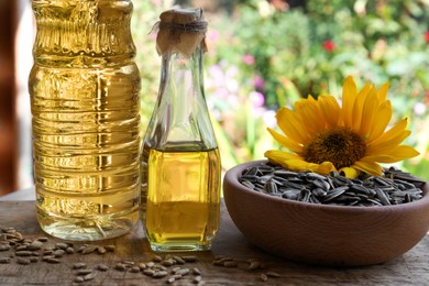 Bottles of sunflower oil and seeds on wooden table outdoors
