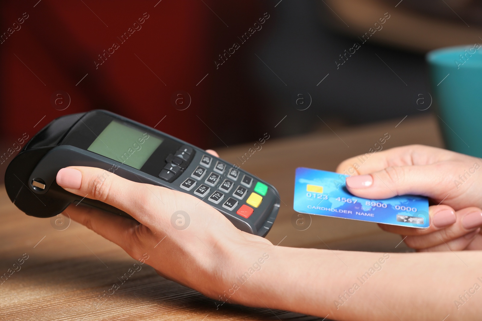 Photo of Woman using modern payment terminal at table indoors, closeup