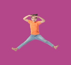 Happy cute girl jumping on purple background