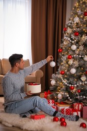 Handsome man decorating Christmas tree at home