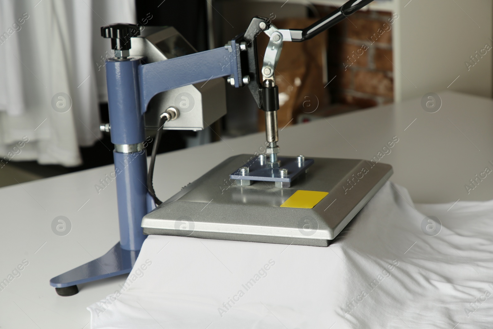 Photo of Printing logo. Heat press with t-shirt on white table, closeup