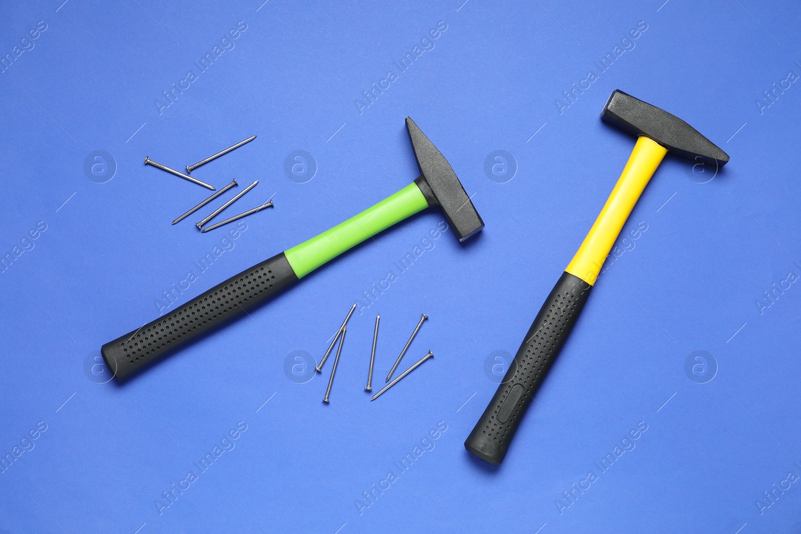 Photo of Hammers and metal nails on blue background, top view