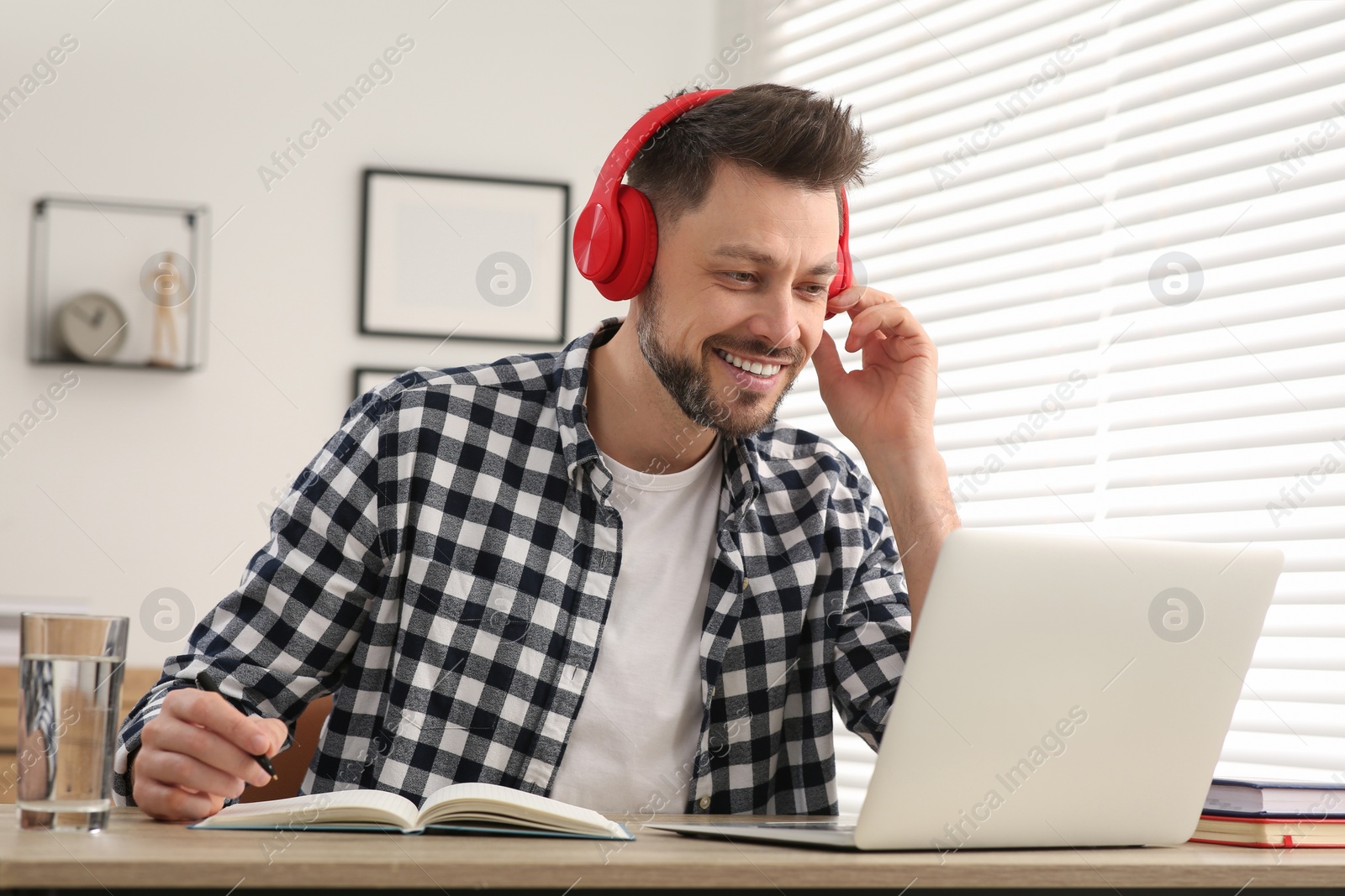 Photo of Man in headphones studying on laptop at home. Online translation course