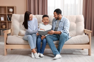 Happy international family reading book on sofa at home