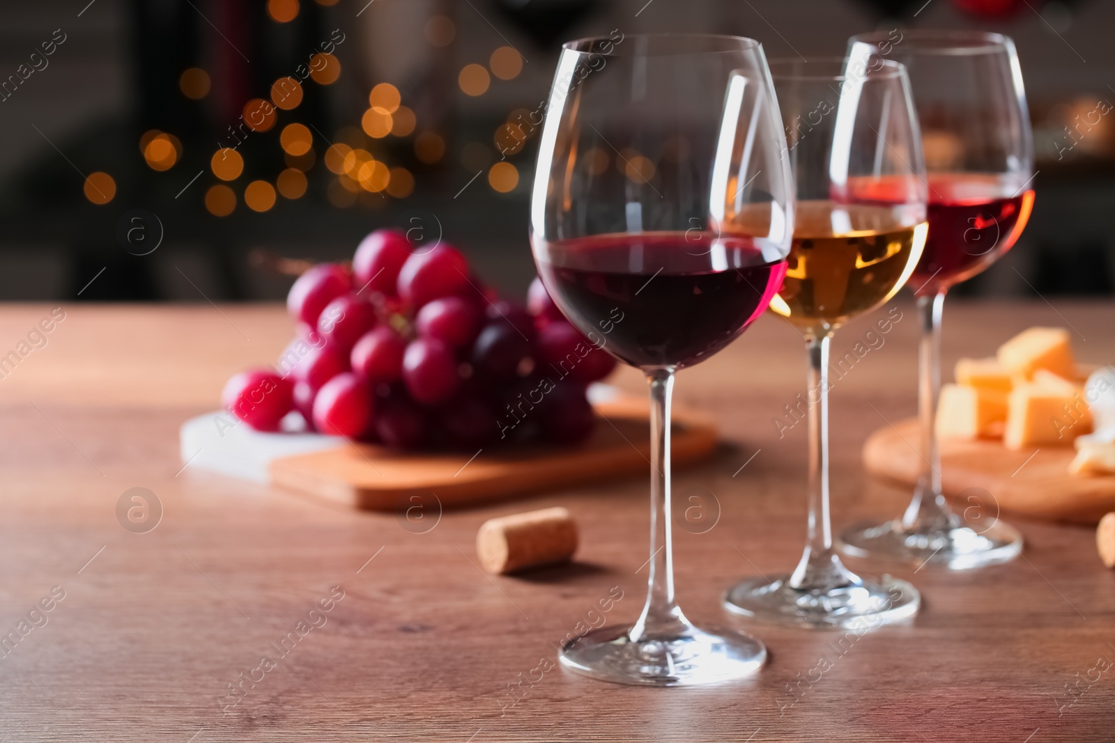 Photo of Glasses with different wines and appetizers on wooden table against blurred background. Space for text