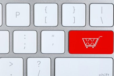 Image of Online store. Red button with shopping cart on computer keyboard, top view