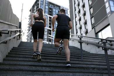 Healthy lifestyle. Couple running up steps outdoors, low angle view