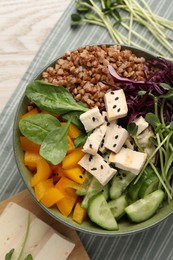 Photo of Delicious vegan bowl with bell pepper, tofu and buckwheat on wooden table, closeup