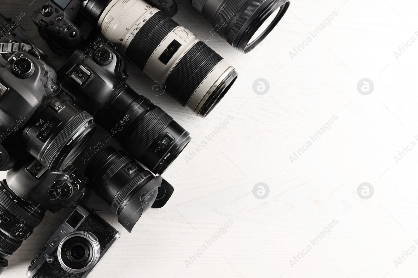 Photo of Modern cameras on white wooden table, flat lay. Space for text