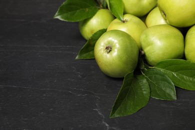 Ripe green apples with leaves on dark grey table. Space for text