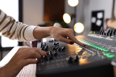 Photo of Woman working with professional mixing console in modern radio studio, closeup