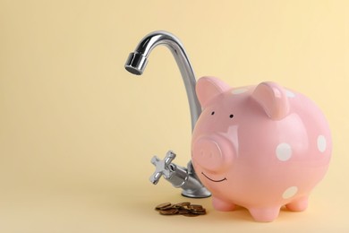 Photo of Water scarcity concept. Piggy bank, tap and coins on beige background, space for text