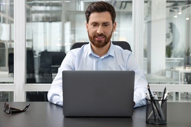 Man working on laptop at black desk in office