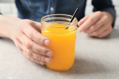 Photo of Woman holding jar of orange juice, closeup