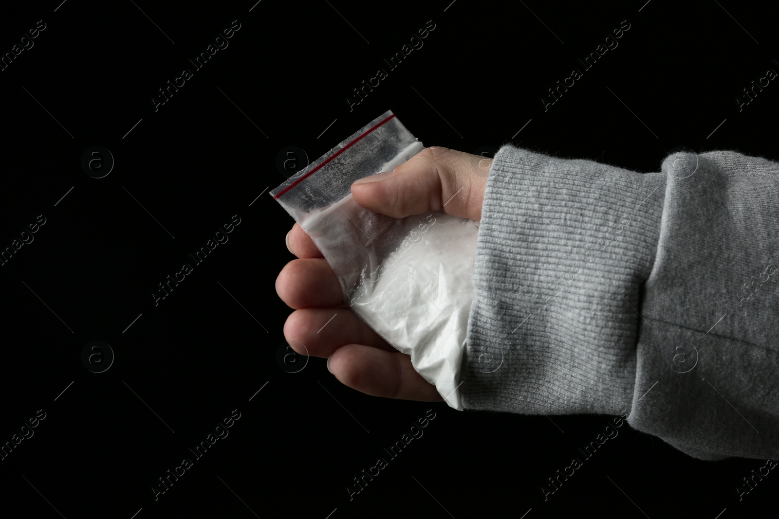 Photo of Drug dealer holding bag with cocaine on black background, closeup