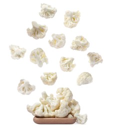 Image of Many fresh cauliflower florets falling onto wooden plate on white background