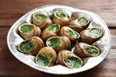 Delicious cooked snails on wooden table, closeup