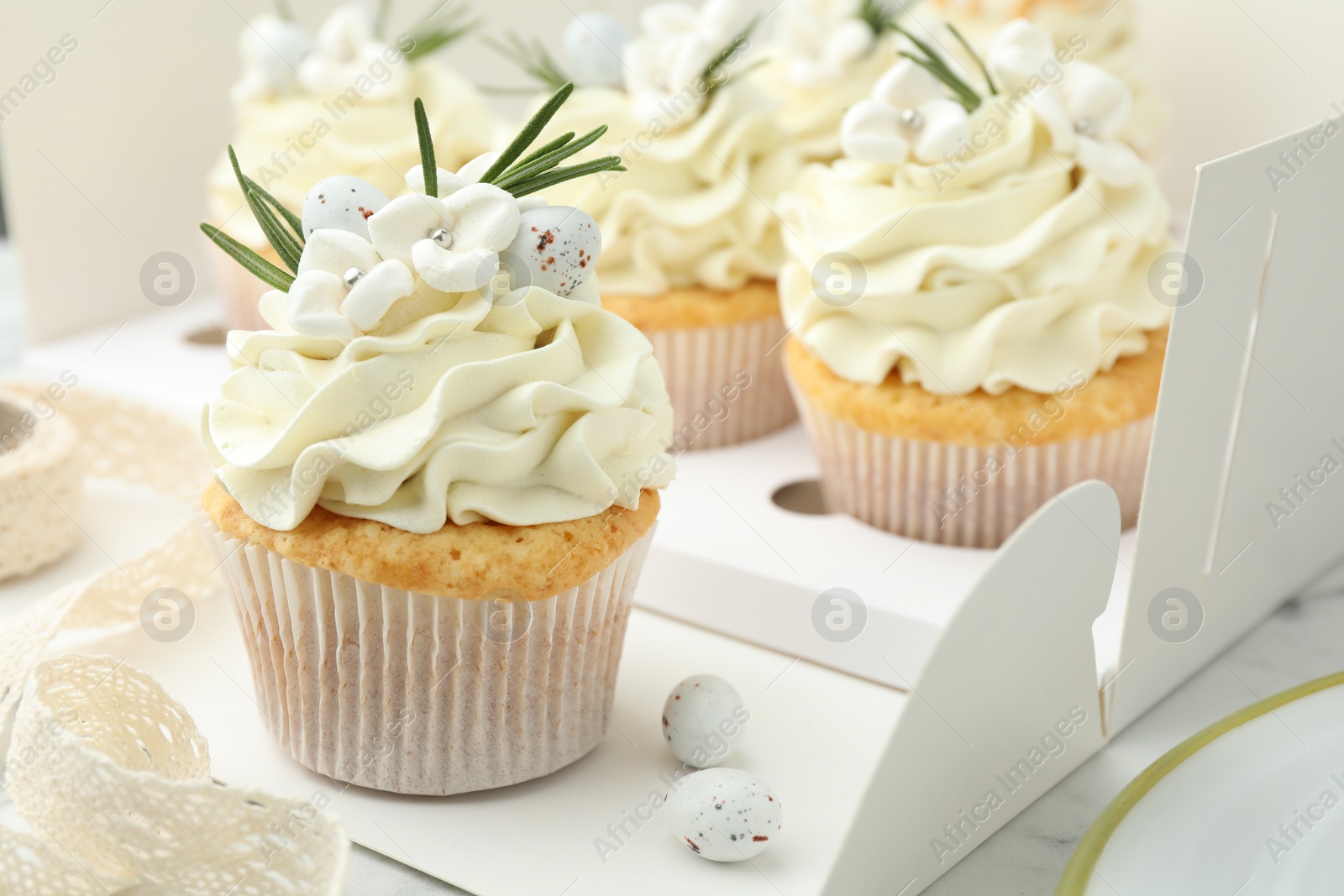 Photo of Tasty Easter cupcakes with vanilla cream on table, closeup