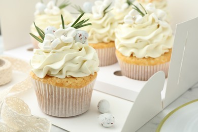 Photo of Tasty Easter cupcakes with vanilla cream on table, closeup