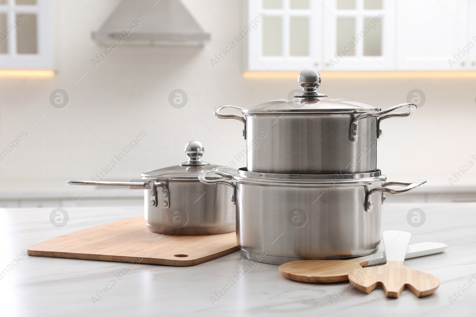 Photo of Set of stainless steel cookware and kitchen utensils on white table indoors