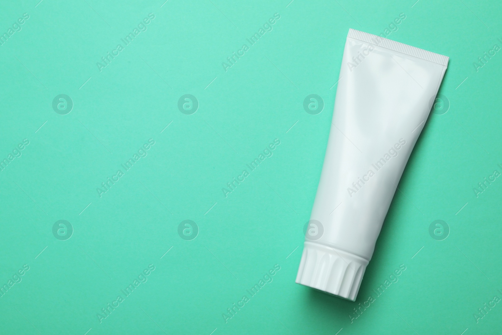 Photo of Blank tube of toothpaste on color background, top view with space for text