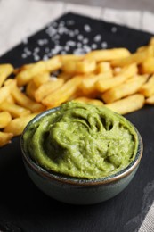 Photo of French fries and avocado dip on serving board, closeup