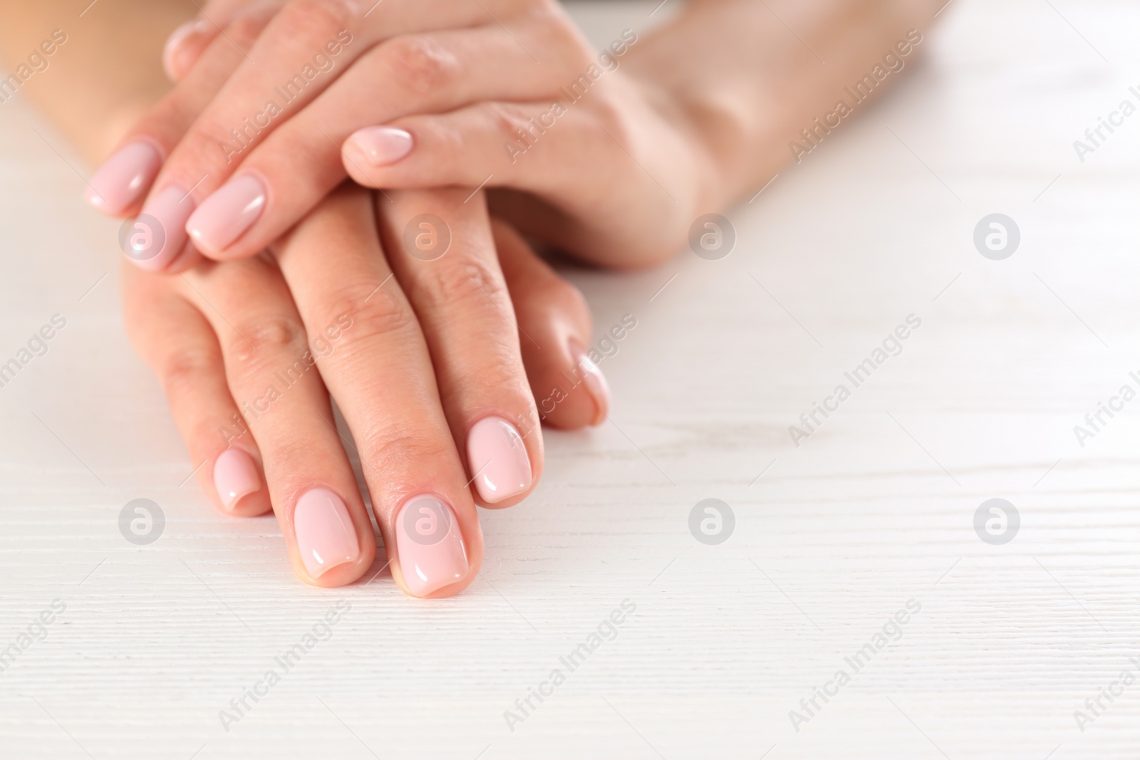Photo of Closeup view of woman with beautiful hands at white wooden table, space for text. Spa treatment