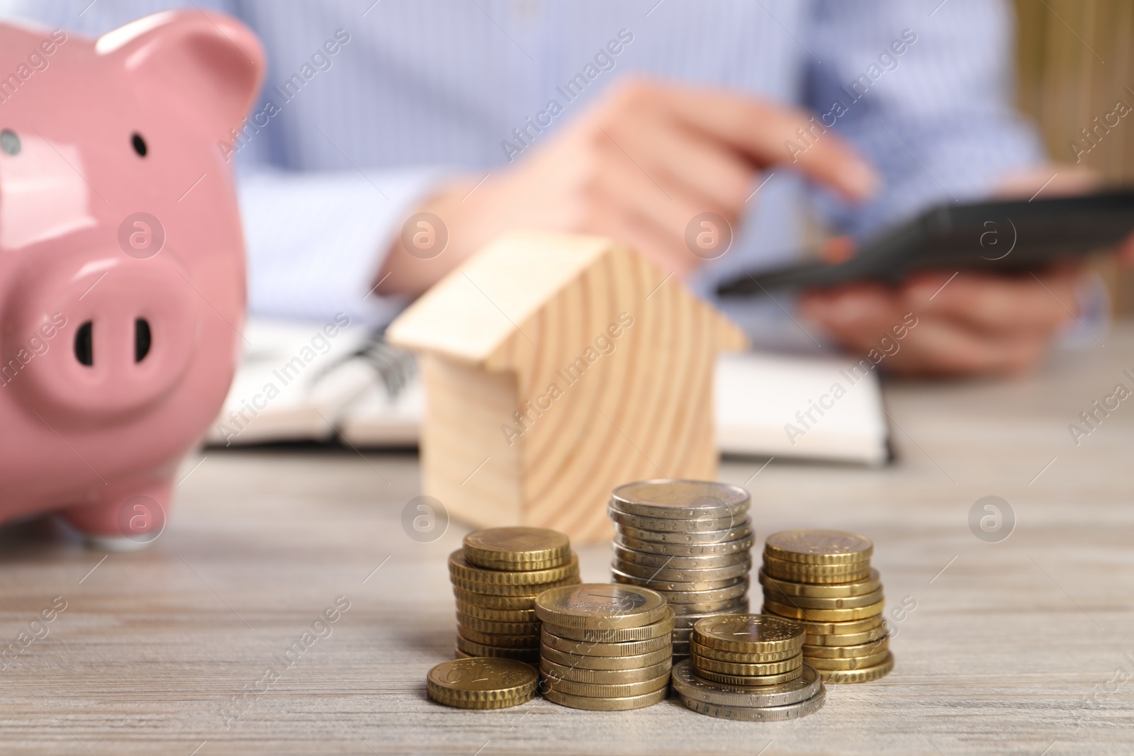 Photo of Savings for house purchase. Woman calculating money at wooden table, focus on coins