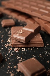 Pieces of tasty chocolate on dark table, closeup